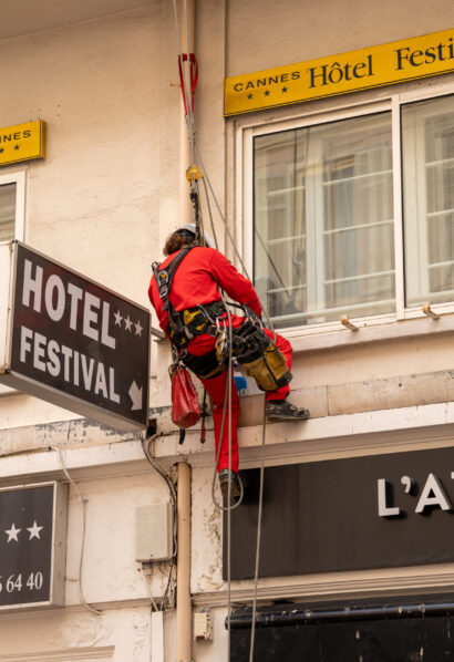 Techniciens cordistes SNADEC en polo rouge et EPI intervenant sur la façade d'un immeuble ancien.