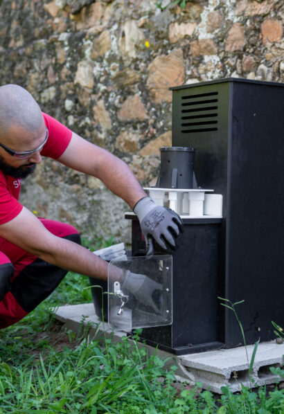 Technicien SNADEC en polo rouge effectuant une maintenance sur un équipement technique extérieur.